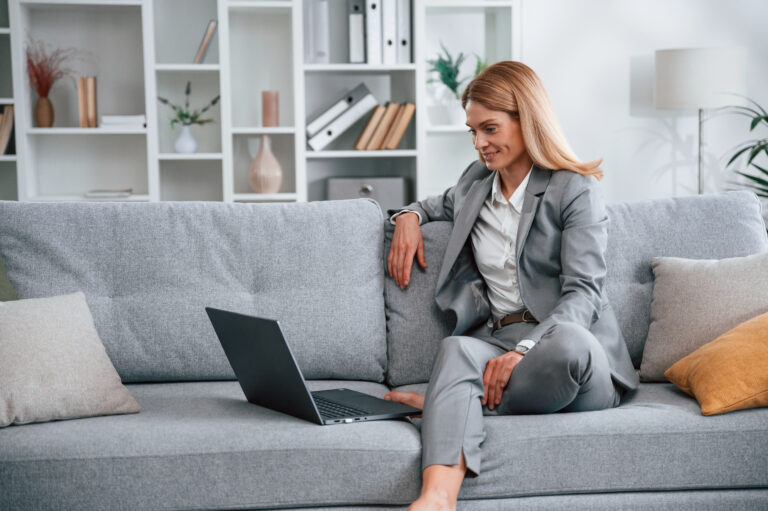 Woman in formal clothes is at home, sitting on the sofa