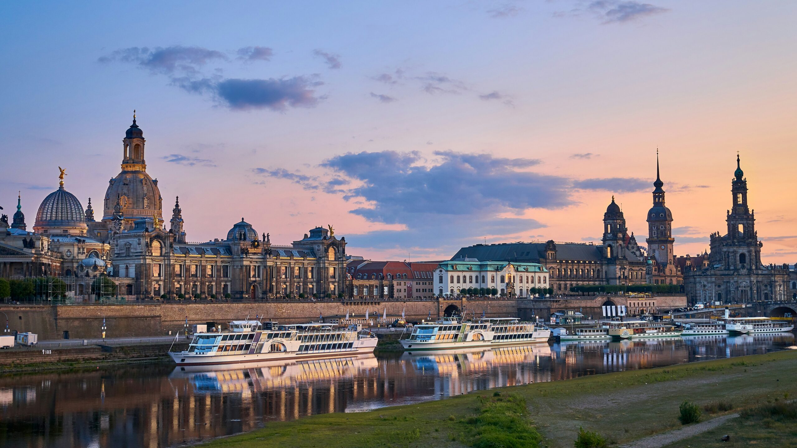 Dresdner Altstadt mit Frauenkirche und historischen Bauwerken an der Elbe bei Sonnenuntergang.